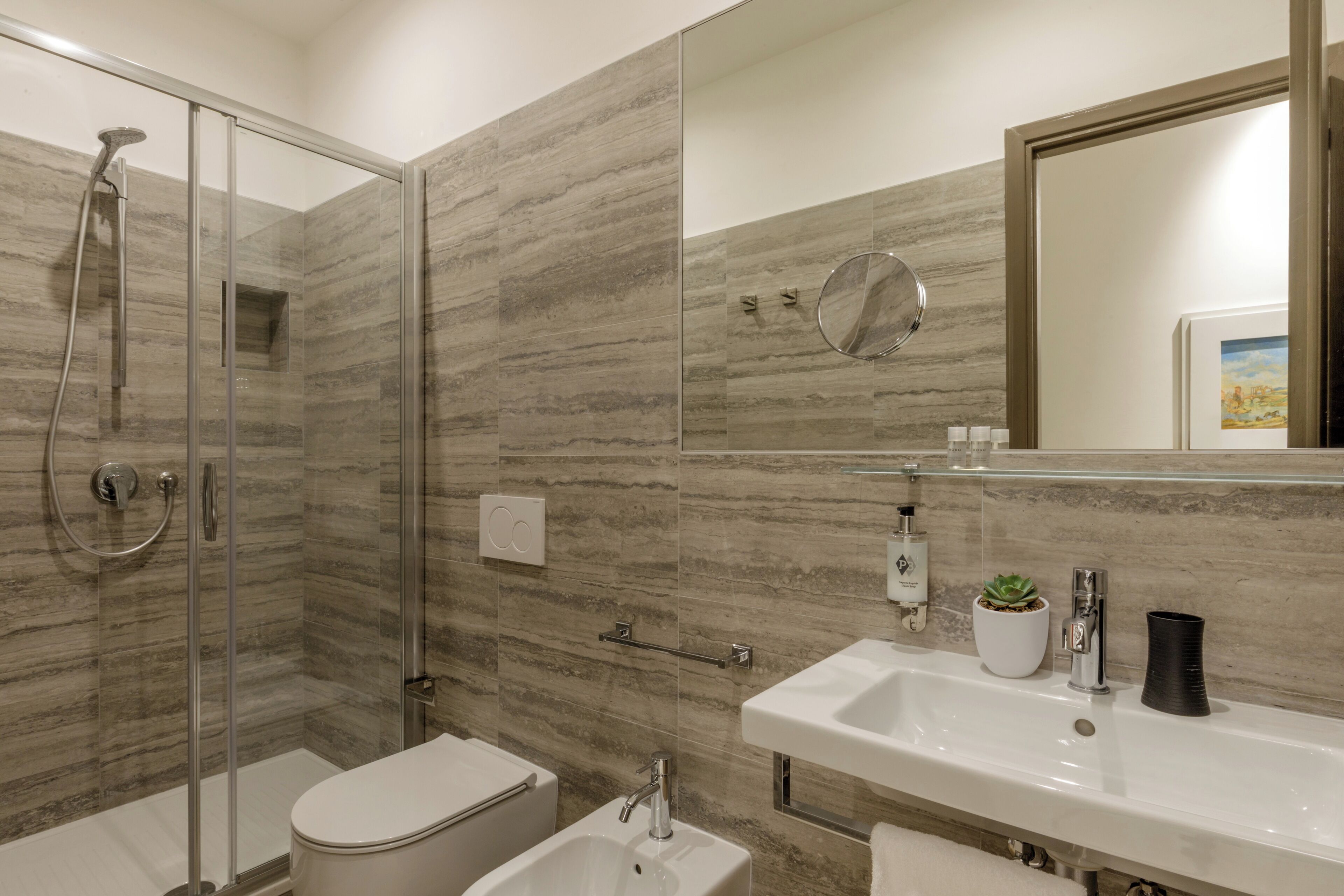A modern bathroom with a glass-enclosed shower, a toilet, and a sink with a mirror above it.