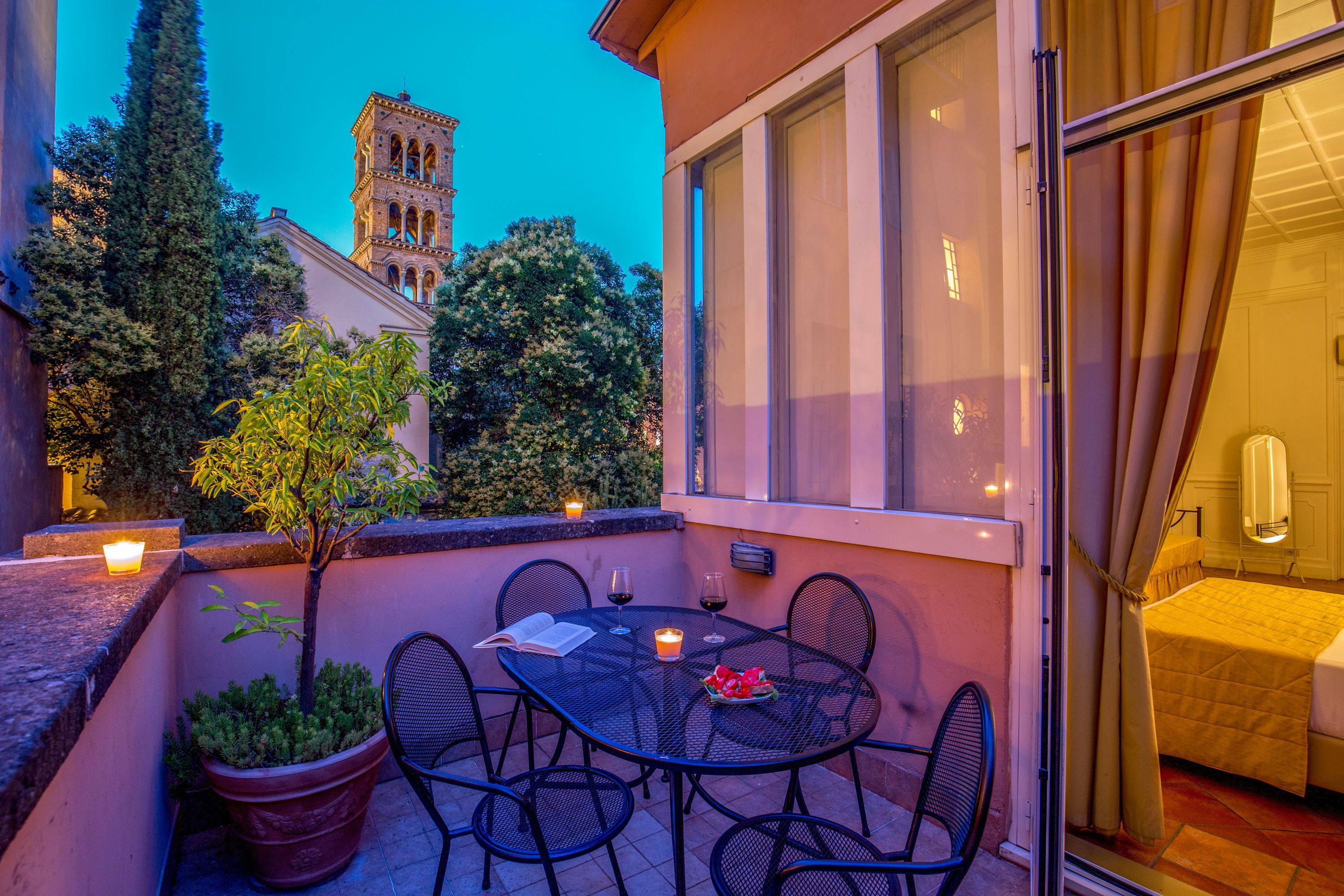 An outdoor patio with a table, chairs, a potted plant, and candles.