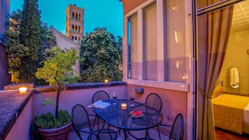 An outdoor patio with a table, chairs, a potted plant, and candles.