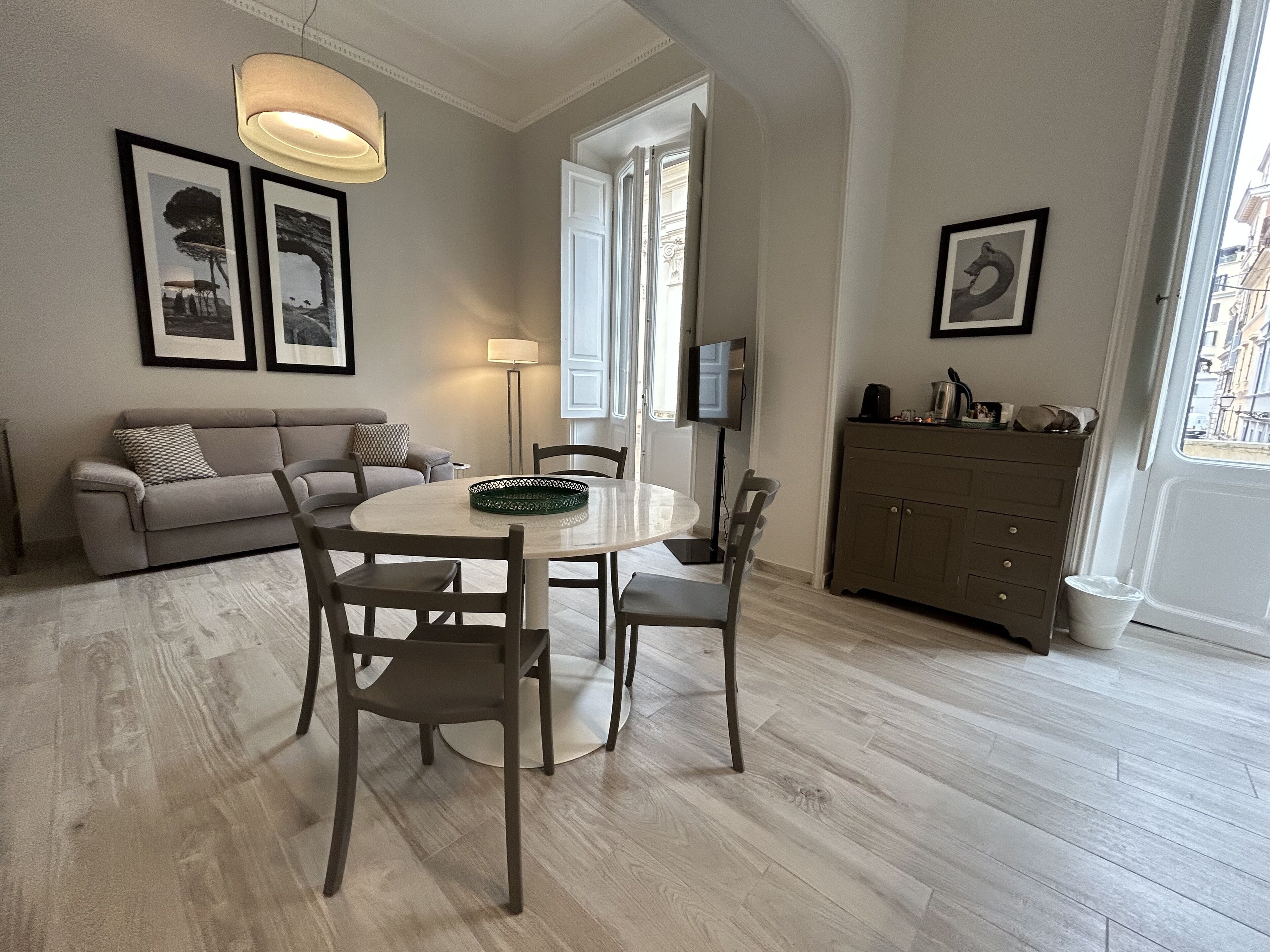 Et spiseområde med et rundt bord, stole, en sofa og et skab.