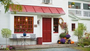 Un bâtiment blanc avec une porte et des fenêtres rouges, portant l’inscription « The Quechee Inn ».