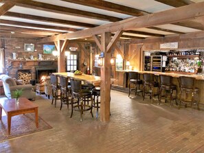 A rustic interior with a bar area, wooden beams, a fireplace, and a dining table with chairs. - The Quechee Inn at Marshland Farm (Quechee)