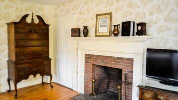 A room with a wooden dresser, a fireplace with a mantel, and a television on a stand.