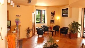 A spacious living area with a reception desk, multiple seating options, and a large window providing natural light. - Hotel Marzia (Scandicci)