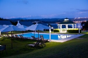Una piscina al aire libre, sillones reclinables de piscina