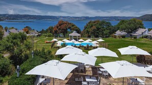 A poolside area with white umbrellas, lounge chairs, and a gazebo overlooking a body of water.