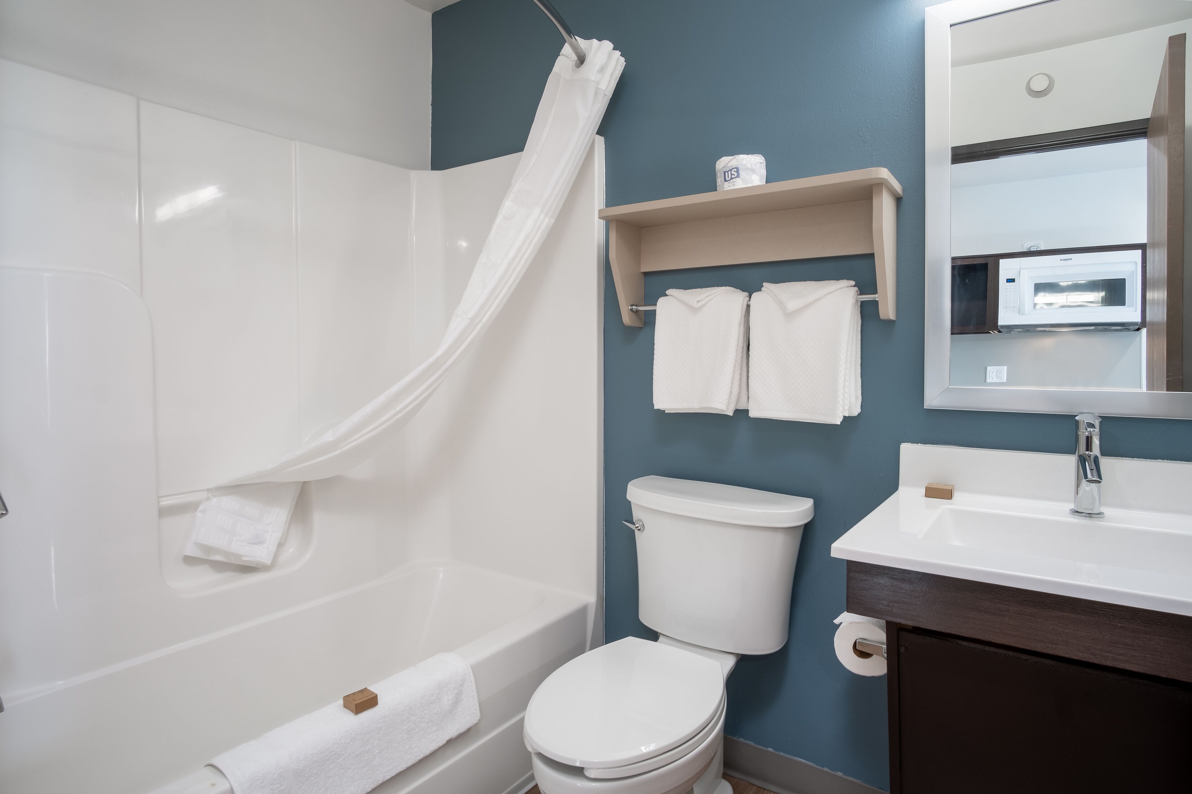 A bathroom with a bathtub, toilet, sink, and a mirror.