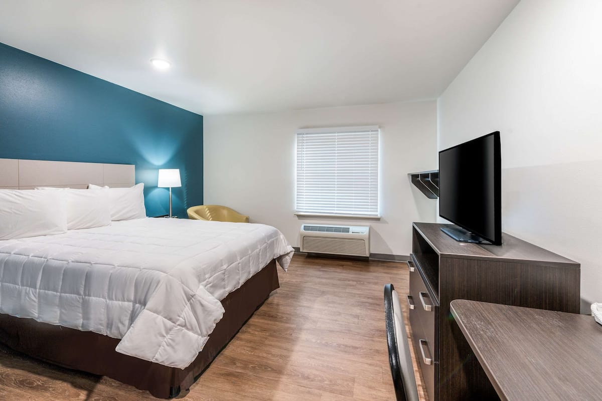 A hotel room with a bed, a television, a desk, and a chair.