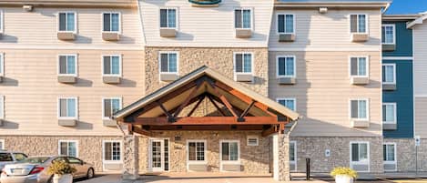 A multi-story hotel with a stone facade and a wooden entrance canopy.