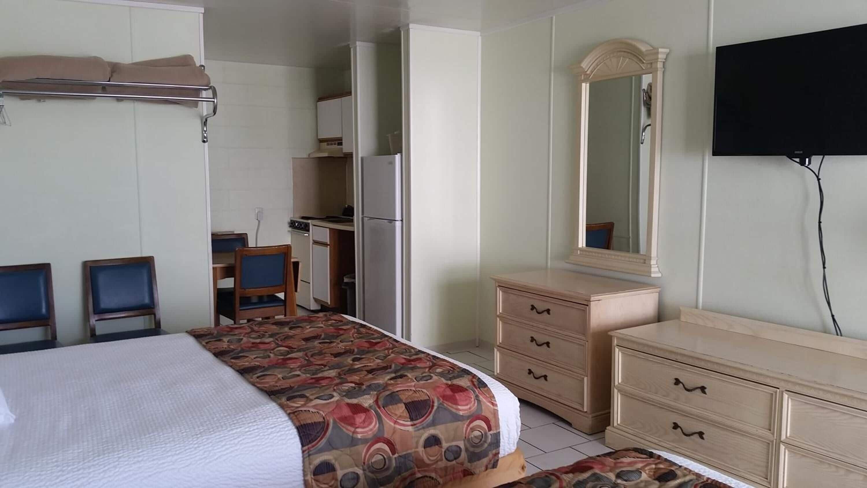 Une chambre d’hôtel comprenant un lit, un bureau, une commode, un miroir et un téléviseur.