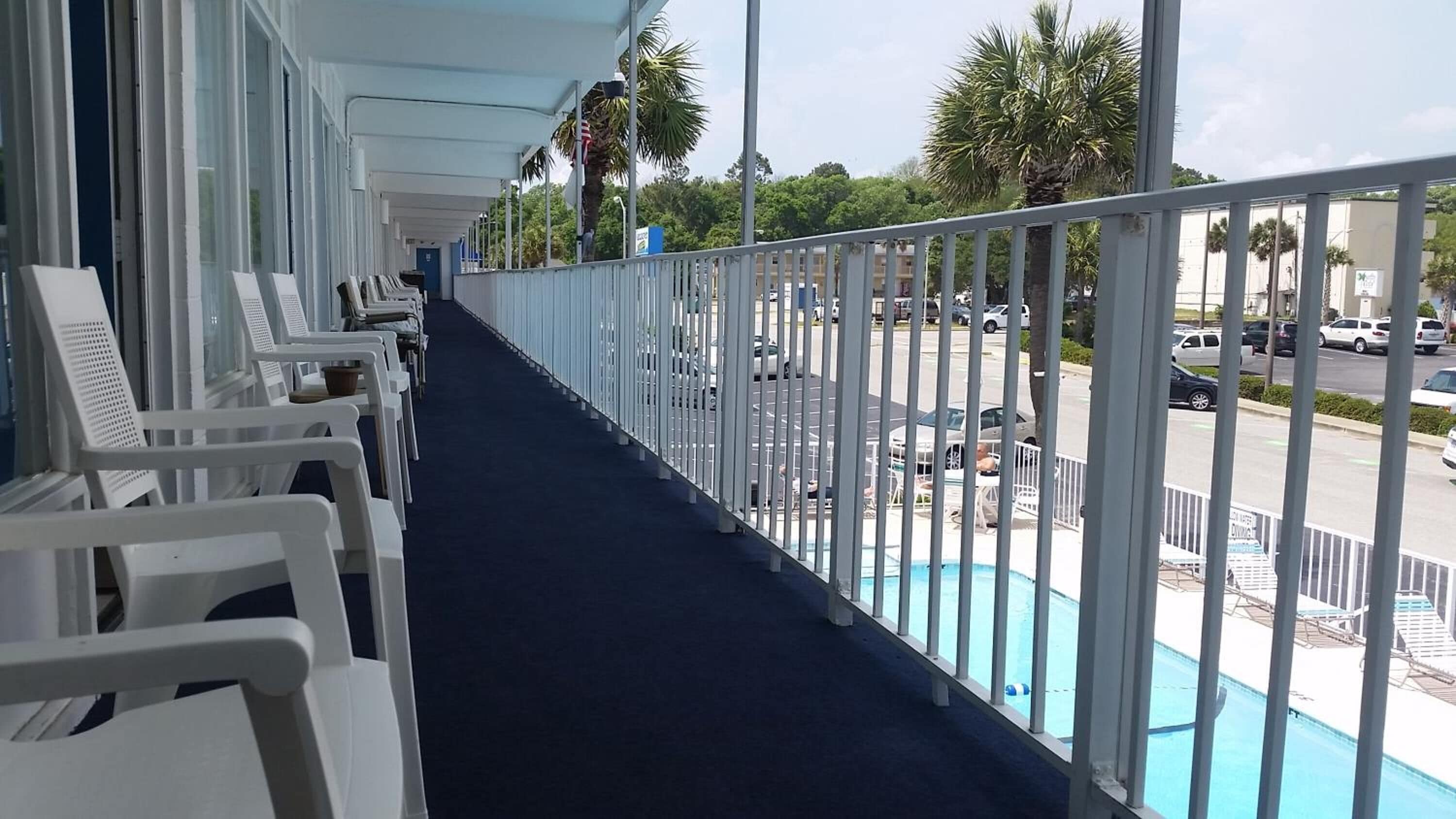 Un balcon avec des chaises blanches et un espace piscine.
