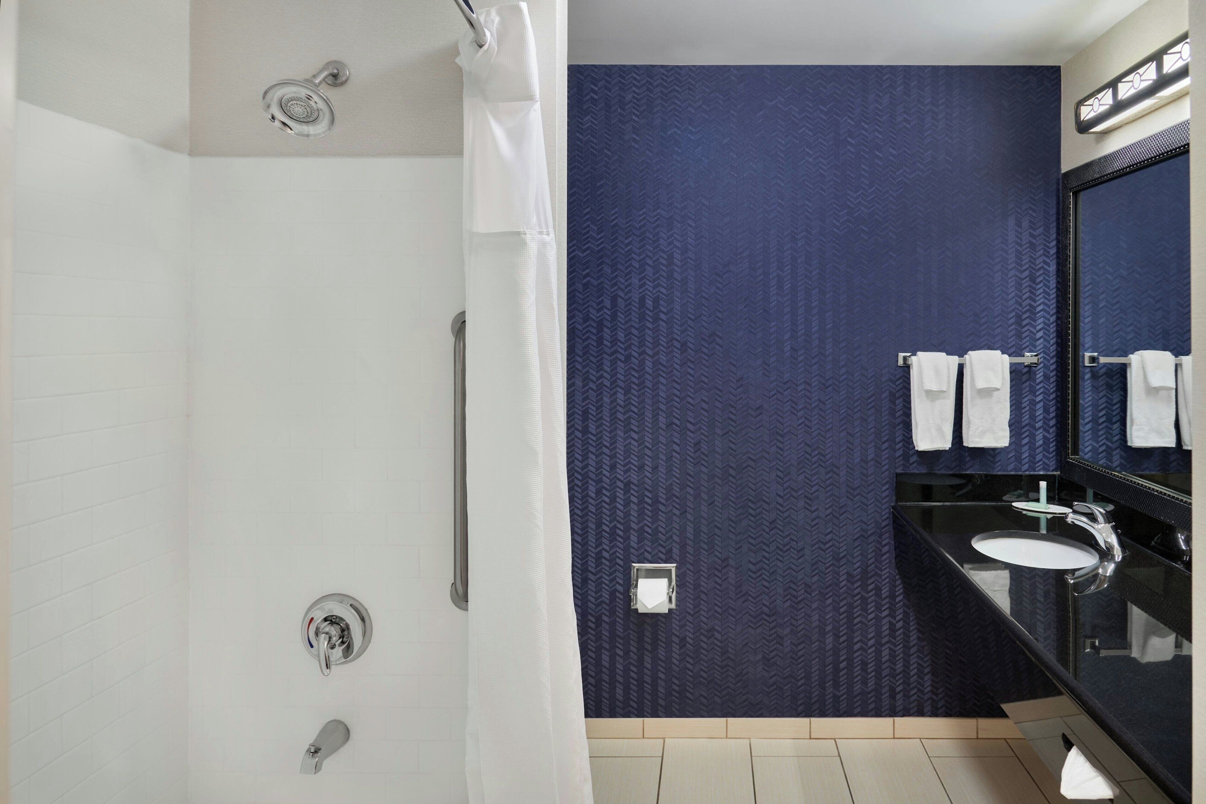 A modern bathroom with a shower, a sink, and a mirror.