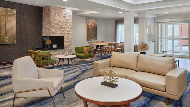A spacious hotel lobby with a large seating area, a fireplace, and a dining table. - Fairfield Inn & Suites by Marriott Cartersville (Cartersville)