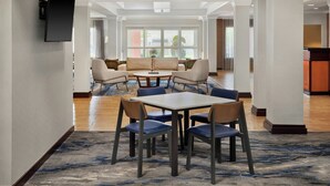 A hotel lobby with a seating area, a flat-screen TV mounted on the wall, and a view of the outside through large windows. - Fairfield Inn & Suites by Marriott Cartersville (Cartersville)