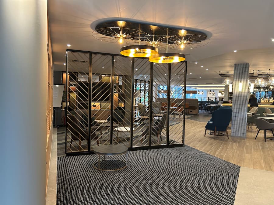 Ein modernes Interieur mit einer zentralen Sitzecke, einer Treppe und einer Bar.