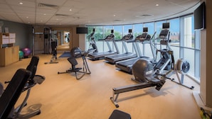 Un gimnasio con cintas de correr, bicicletas estáticas y máquinas de pesas.