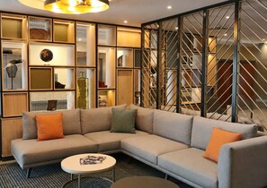 A modern living room with a sectional sofa, a coffee table, and a decorative wall with shelves.