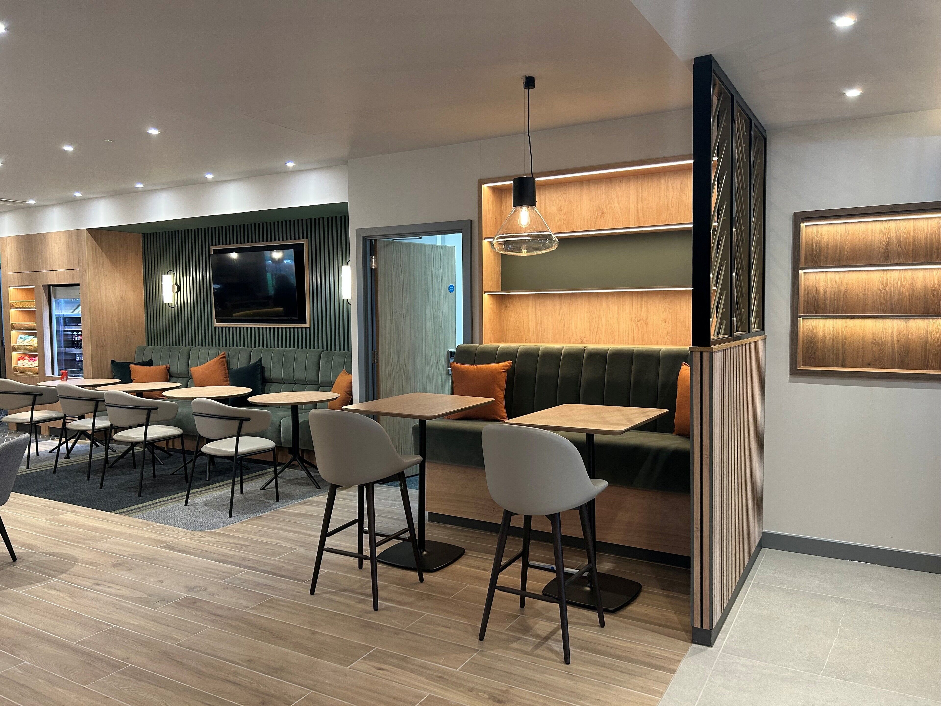 A modern interior with seating areas, tables, and a TV screen.
