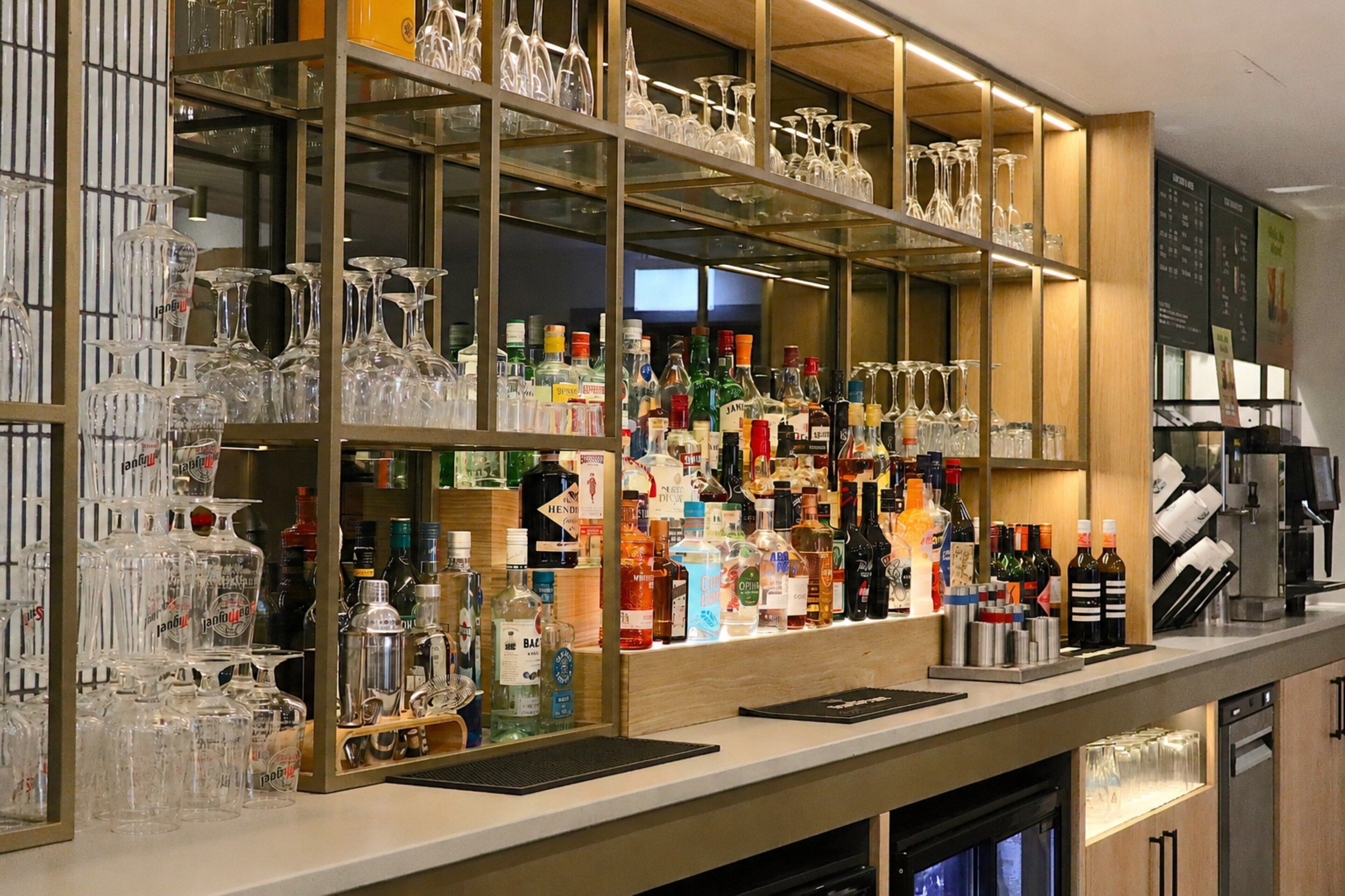 A bar area with shelves of various liquor bottles and a display of wine glasses.
