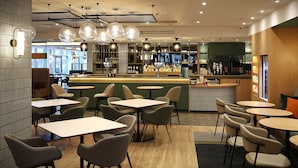 Un interior de restaurante moderno con varias zonas de estar, una barra y vistas al exterior.