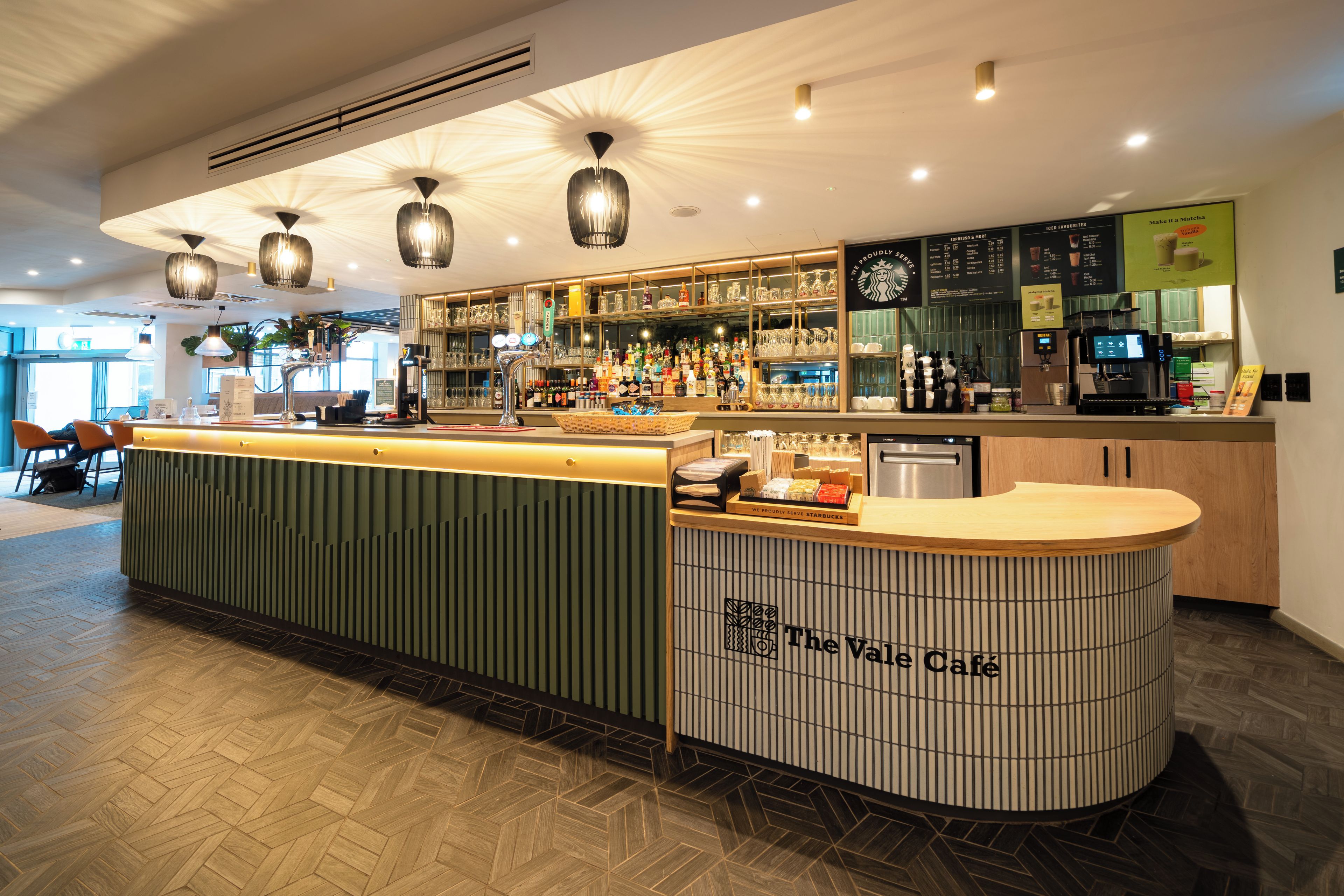 A bar area with a counter, shelves with bottles, and a coffee machine.