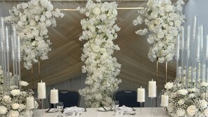 Mesa de recepción de boda con arreglos florales blancos, velas altas y letrero con la inscripción 'Mr & Mrs'.