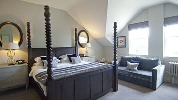 A bedroom with a four-poster bed, a sofa, a nightstand, a lamp, and a mirror.