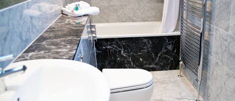 Une salle de bain avec un lavabo, des toilettes et une baignoire, le tout de couleur blanche.