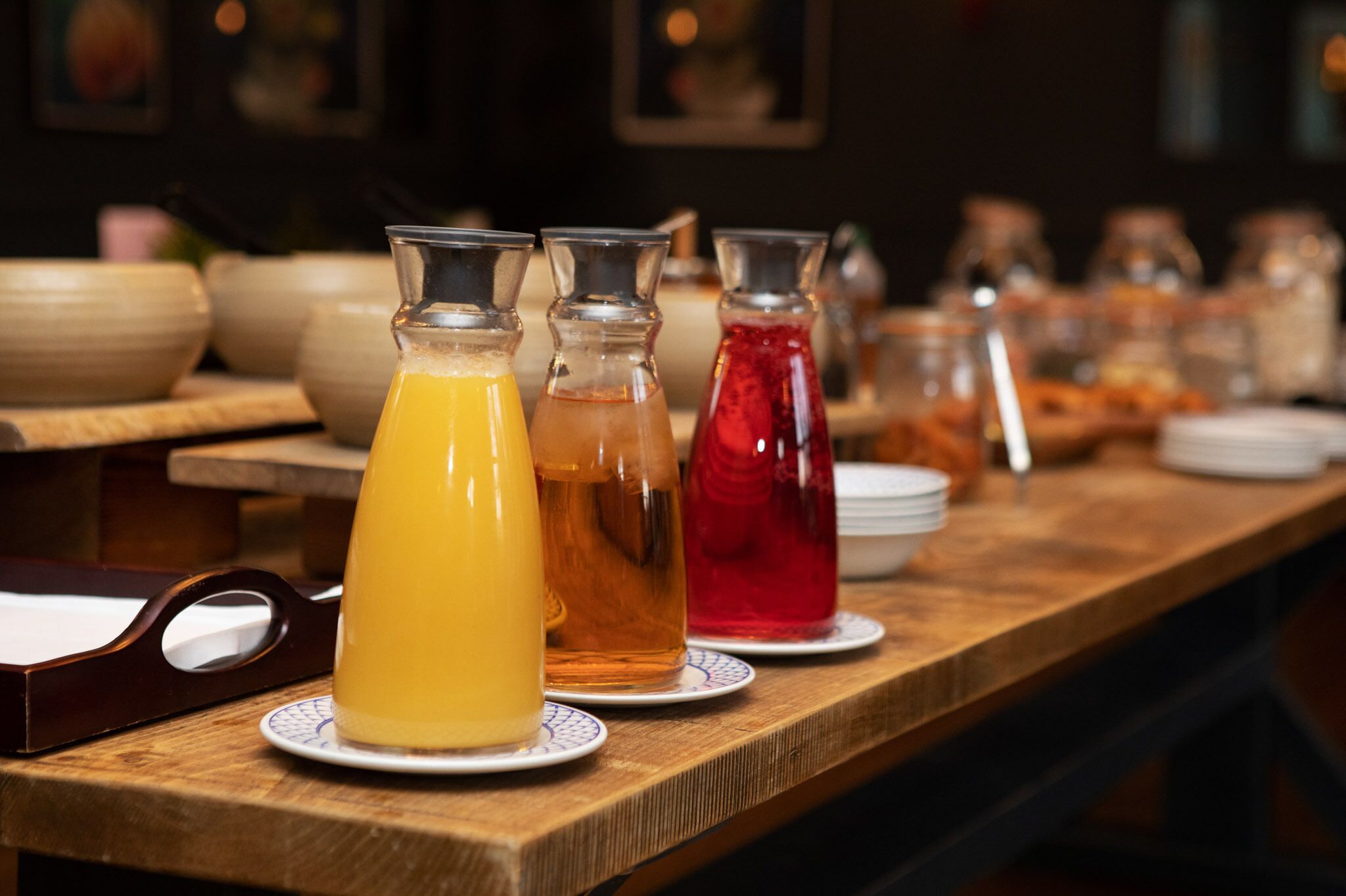 Una mesa buffet de madera con tres botellas de bebidas.