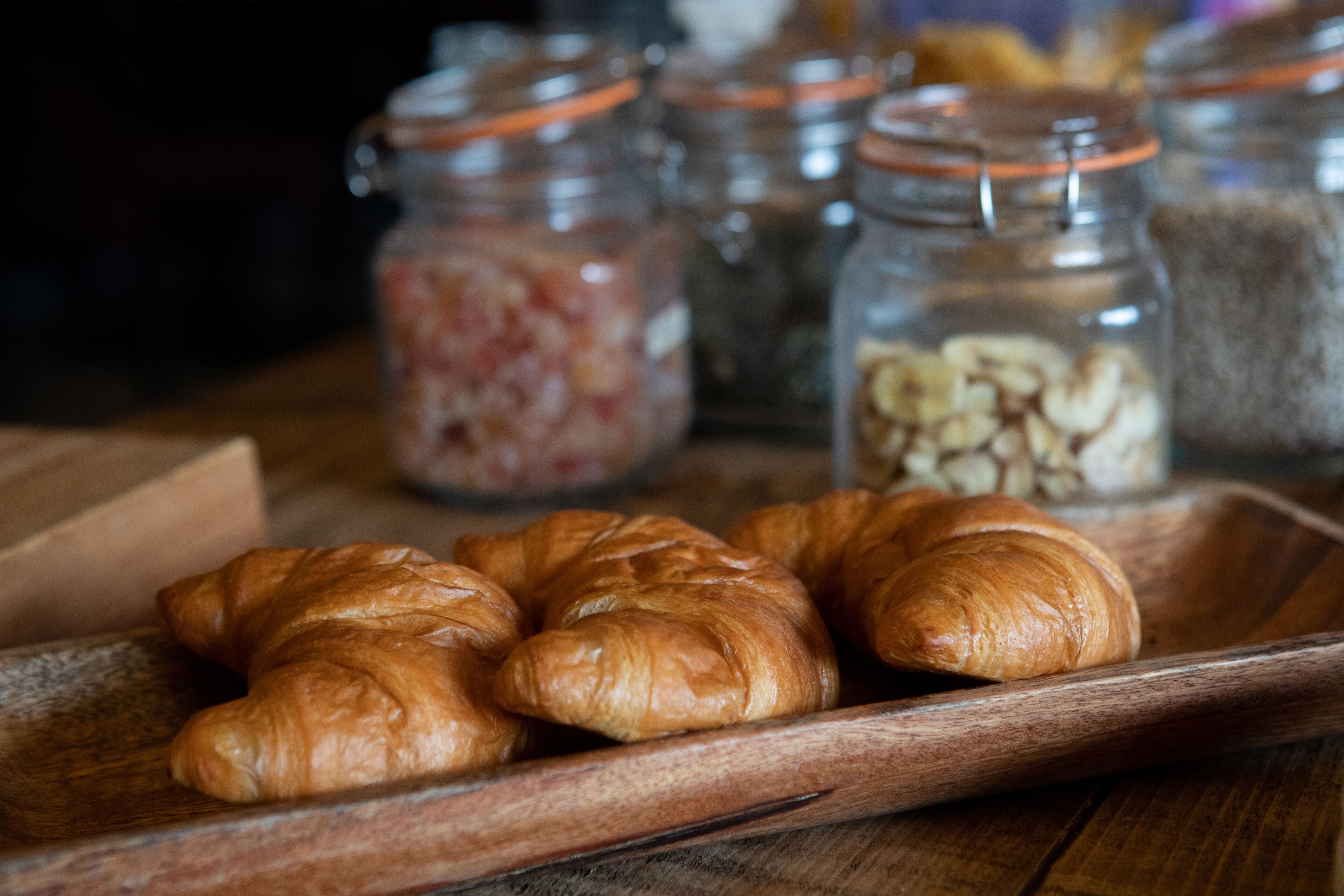A wooden tray with croissants and jars of ingredients.