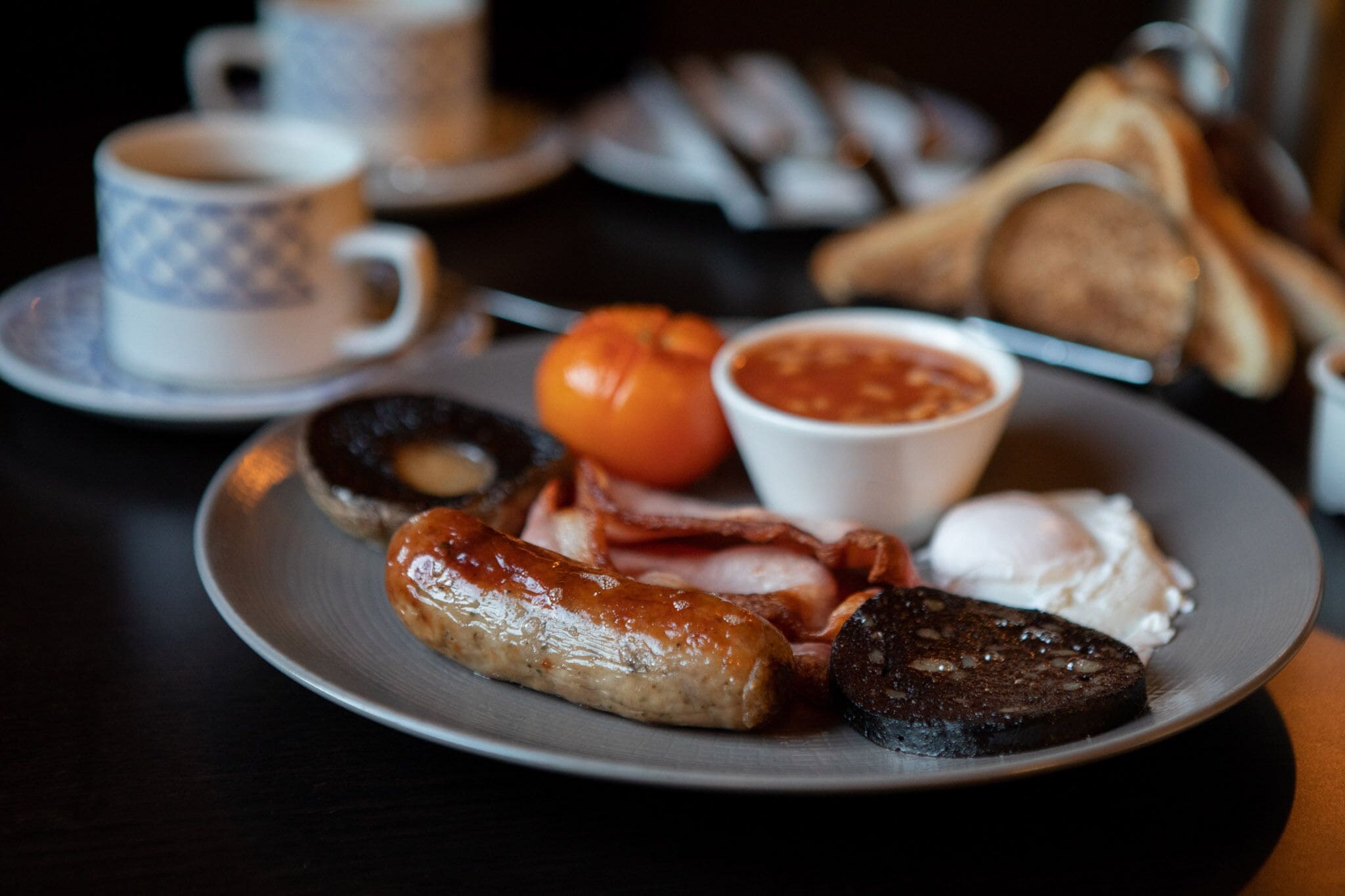 Ein Teller mit Frühstücksleckereien, darunter Würstchen, Speck, Eier und Toast.