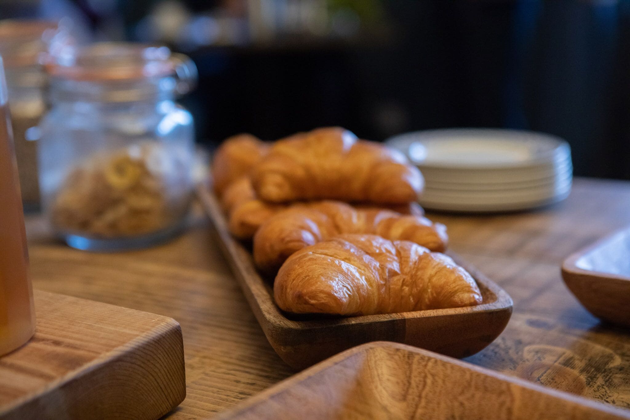 A wooden tray with croissants on a wooden table.