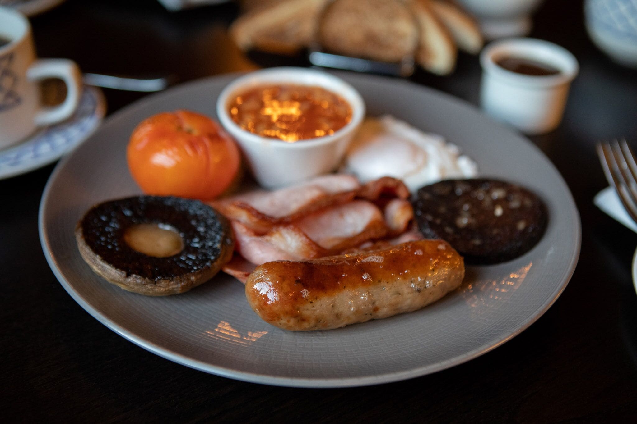Prato de comida de café da manhã com salsichas, bacon, ovos e torradas.