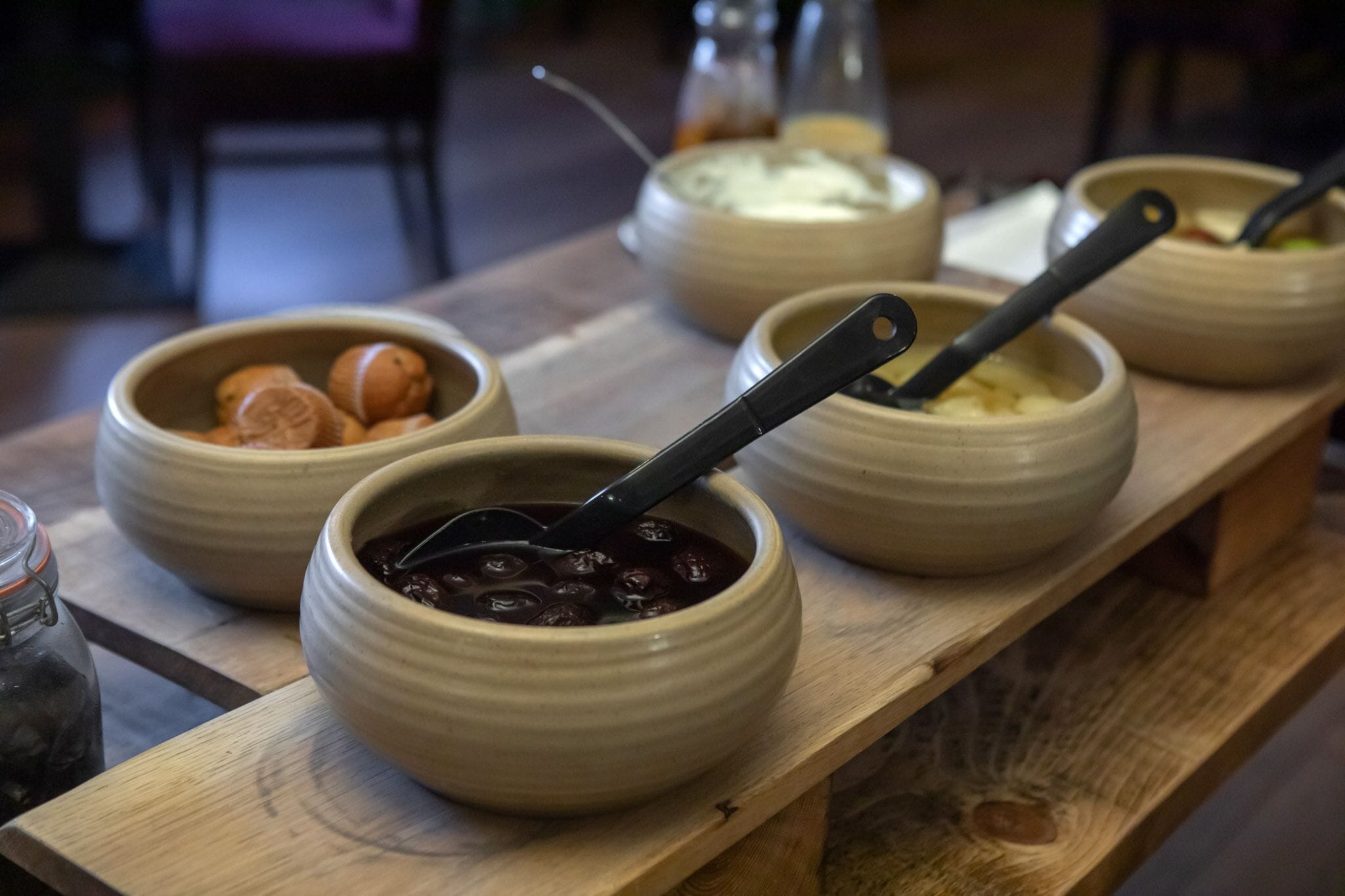 A wooden table with several ceramic bowls containing different foods.