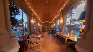 Une pièce chaleureuse et bien éclairée, dotée de planchers en bois et de grandes fenêtres, où l’on peut admirer un sapin de Noël et des décorations de fêtes.