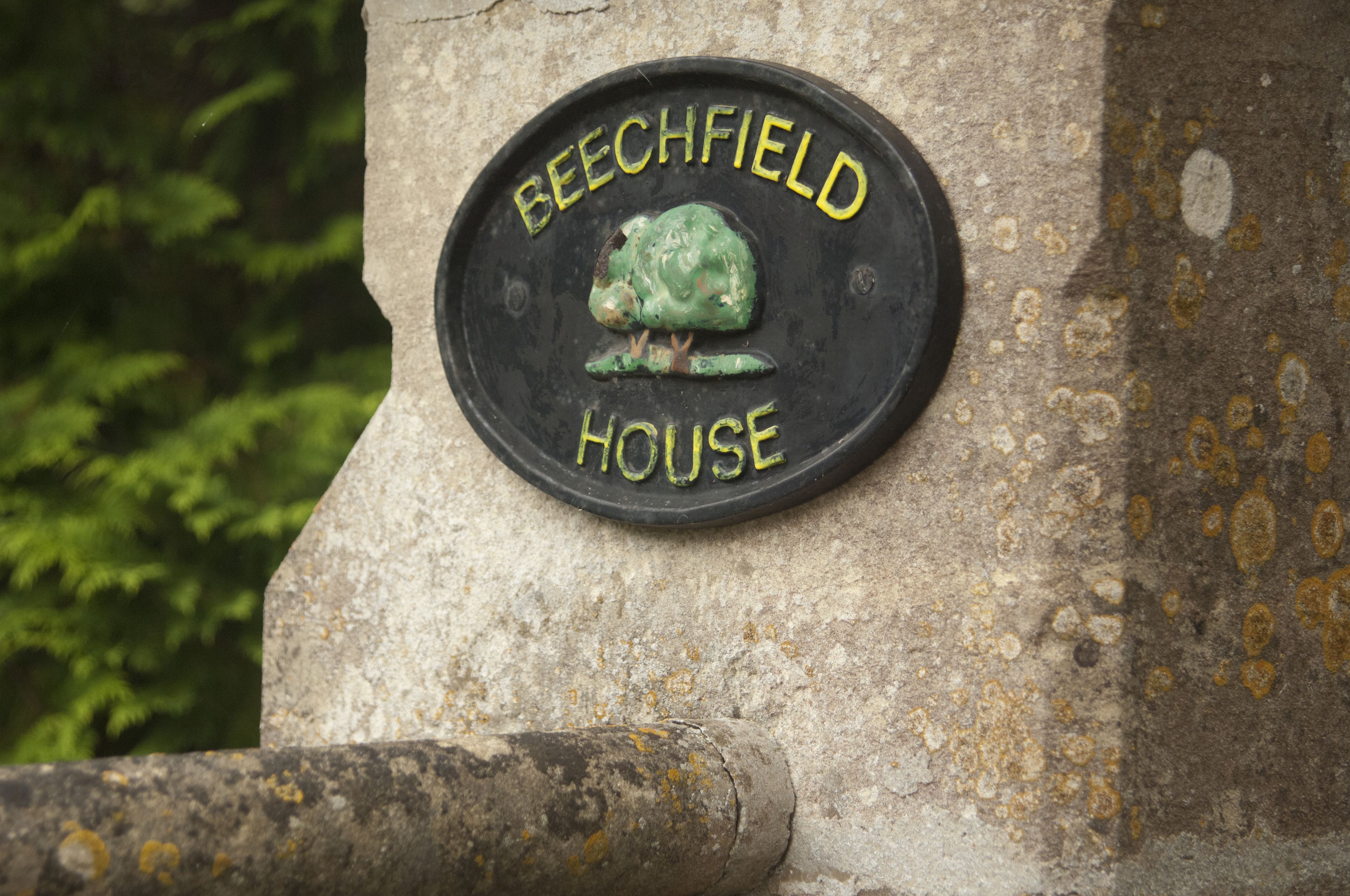 Une plaque portant l’inscription « Beechfield House » est fixée à un mur de pierre.