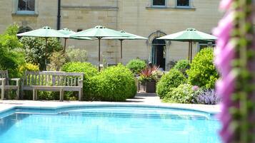 Relax by the serene pool surrounded by lush greenery and flowering plants.
