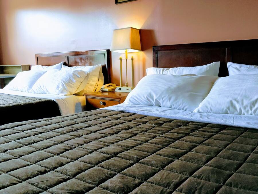 A hotel room with two single beds, a nightstand with a lamp, and a desk with a telephone.