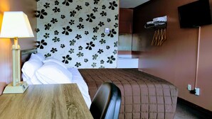 A hotel room with a bed, a bedside table with a lamp, a wardrobe, a TV mounted on the wall, and a towel rack with towels. - Kings Inn Midland (Midland)