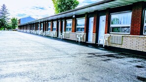 A motel with a row of single rooms, each with a window and a door. - Kings Inn Midland (Midland)