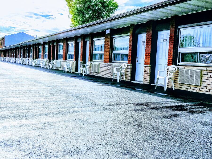Un motel con una hilera de habitaciones individuales, cada una con ventana y puerta.