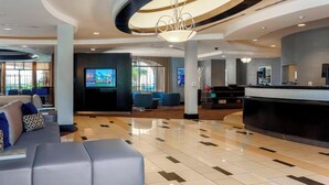 A modern lobby with a reception desk, seating area, and a large screen.