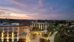 A Courtyard by Marriott hotel with a well-lit courtyard, outdoor seating, and a view of the surrounding area.