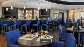 A bar area with multiple seating options, a well-stocked bar, and a television screen.