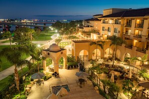 A hotel courtyard with outdoor seating, palm trees, and a view of the sea. - Courtyard by Marriott San Diego Airport/Liberty Station (San Diego)