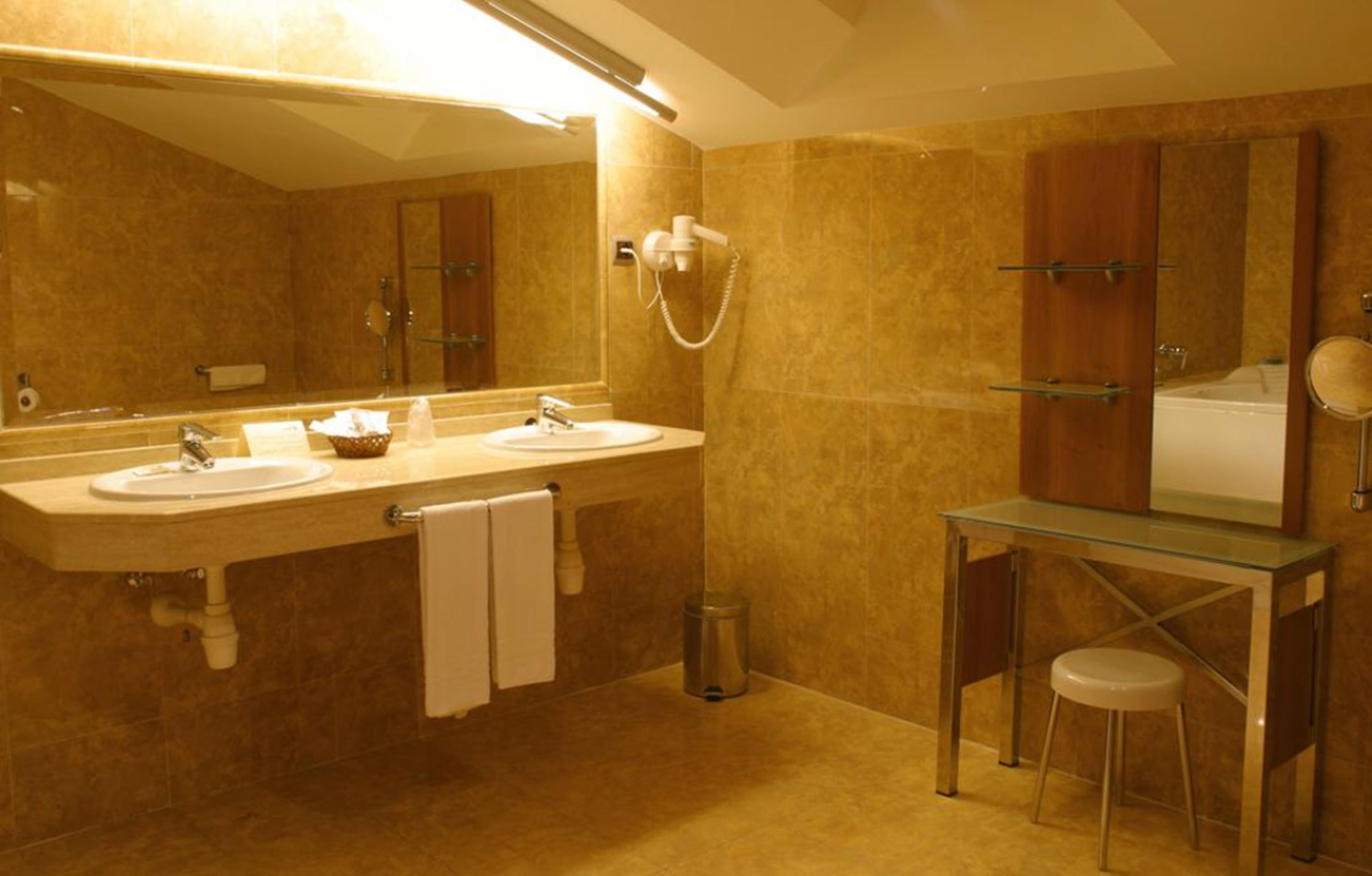 Une salle de bain avec deux lavabos, un meuble-lavabo en verre, un miroir, une douche et des toilettes.
