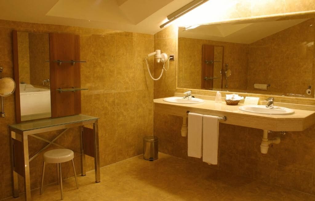 A bathroom with two sinks, a glass vanity, a mirror, and a shower.