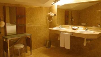 A bathroom with two sinks, a glass vanity, a mirror, and a shower.