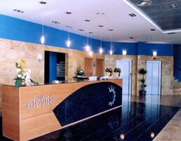 Un comptoir de réception d’hôtel avec un revêtement de marbre, un mur d’accent bleu et un sol en marbre noir.