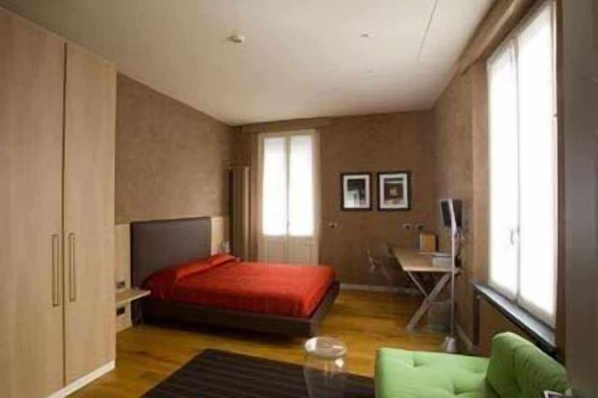A bedroom with a bed, a desk, a chair, and a wardrobe.